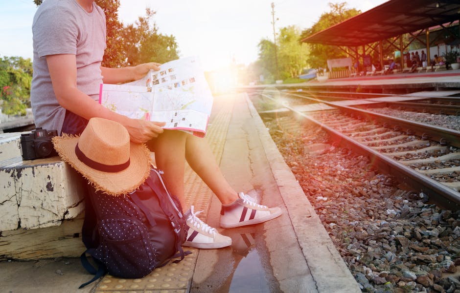 Person sitting at train station platform reading map, embracing travel adventure