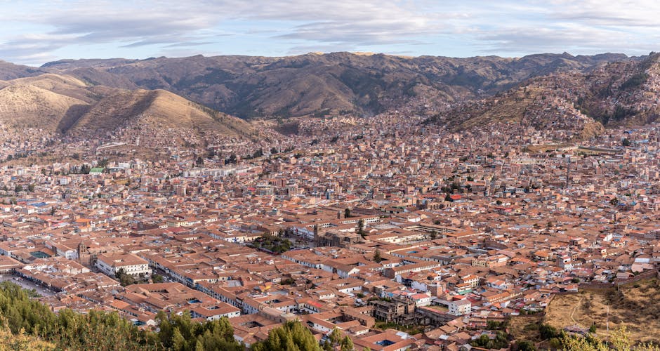 Stunning aerial view of Cusco, Peru, showcasing its historic red-tiled roofs surrounded by mountainous landscapes