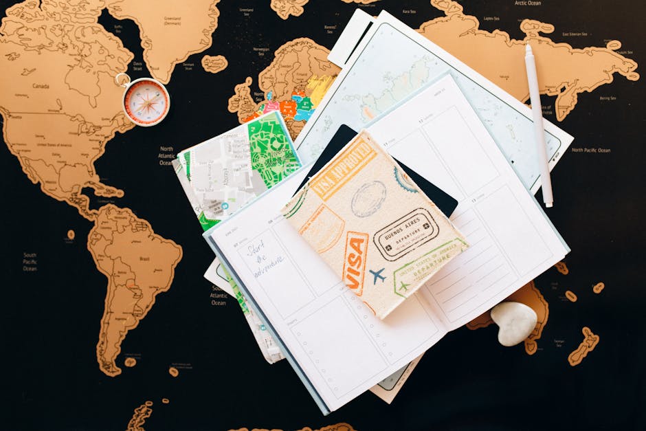 A flat lay of travel planning items on a map, featuring a compass, notebook, and guide for wanderlust enthusiasts